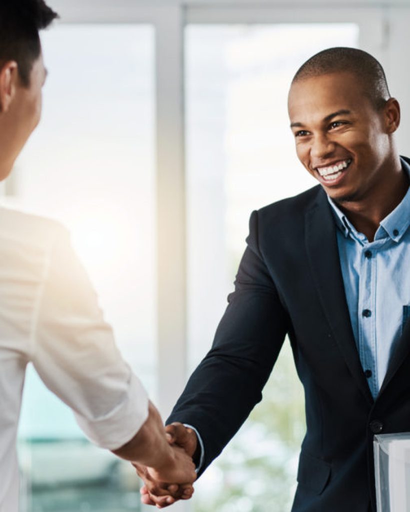 Shot of two young businessmen shaking hands in a modern office